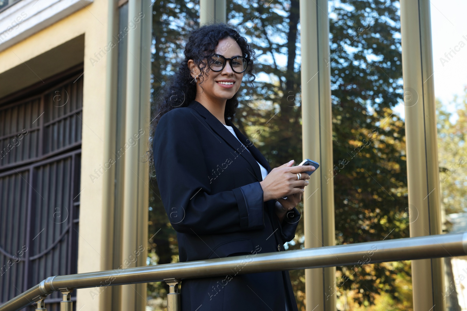 Photo of Portrait of young woman with phone wearing stylish suit outdoors