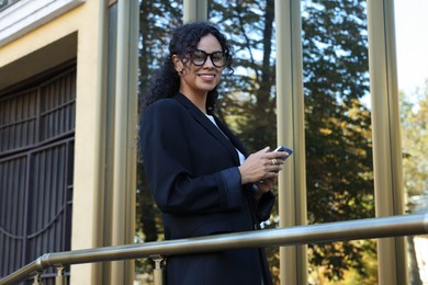 Photo of Portrait of young woman with phone wearing stylish suit outdoors