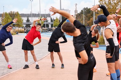 Photo of Group of people exercising and stretching outdoors