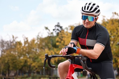 Photo of Athletic man with helmet and bicycle outdoors, space for text