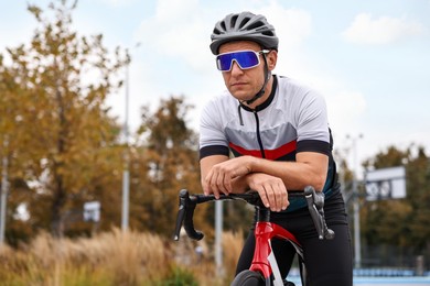 Photo of Athletic man with helmet and bicycle outdoors, space for text