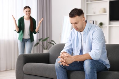 Husband ignoring his emotional wife at home, selective focus