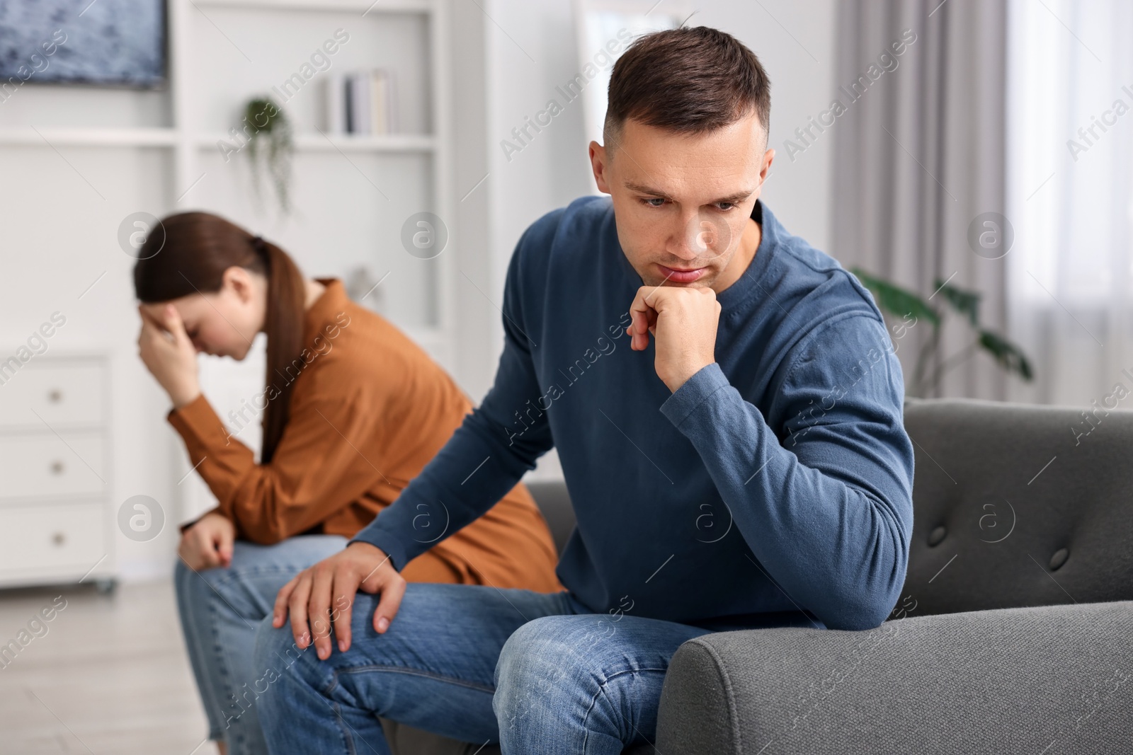 Photo of Offended couple ignoring each other at home, selective focus