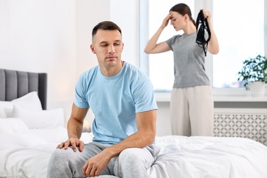 Photo of Frustrated wife finding mistress bra and unfaithful husband in bedroom, selective focus