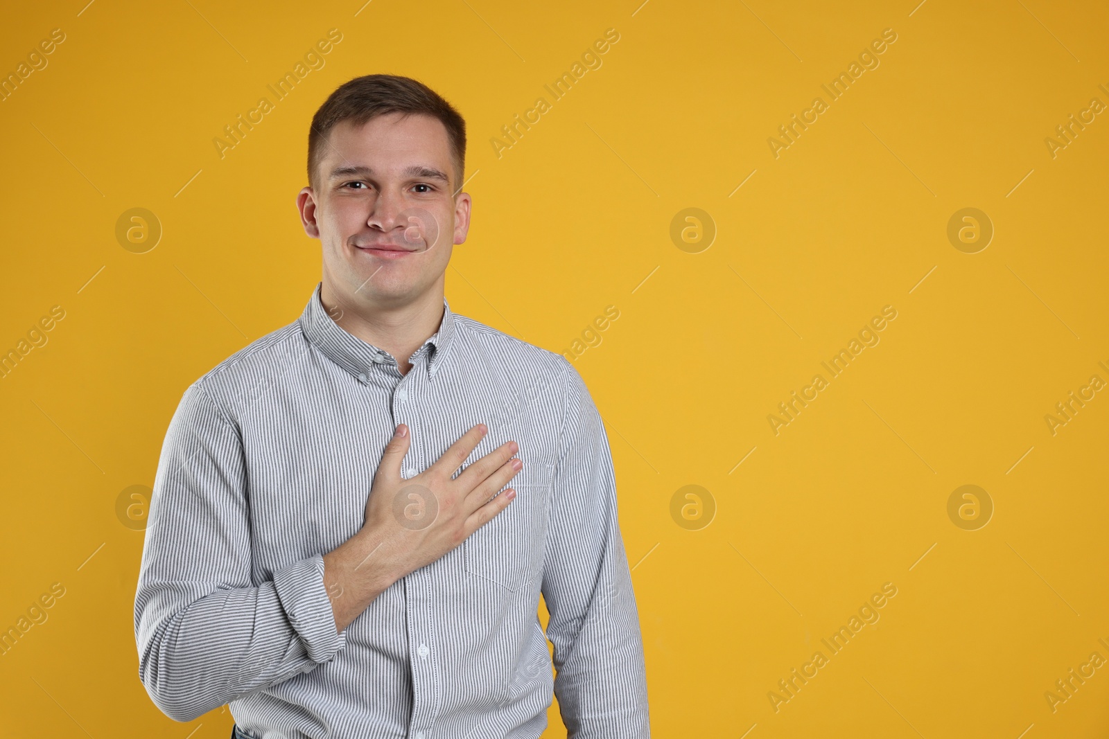 Photo of Man making promise on orange background, space for text. Oath gesture