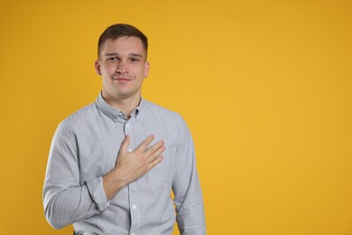 Photo of Man making promise on orange background, space for text. Oath gesture