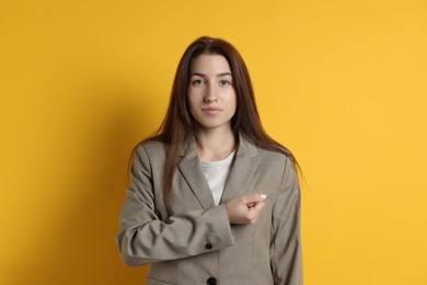 Woman making promise on orange background. Oath gesture