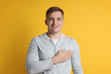 Photo of Man making promise on orange background. Oath gesture