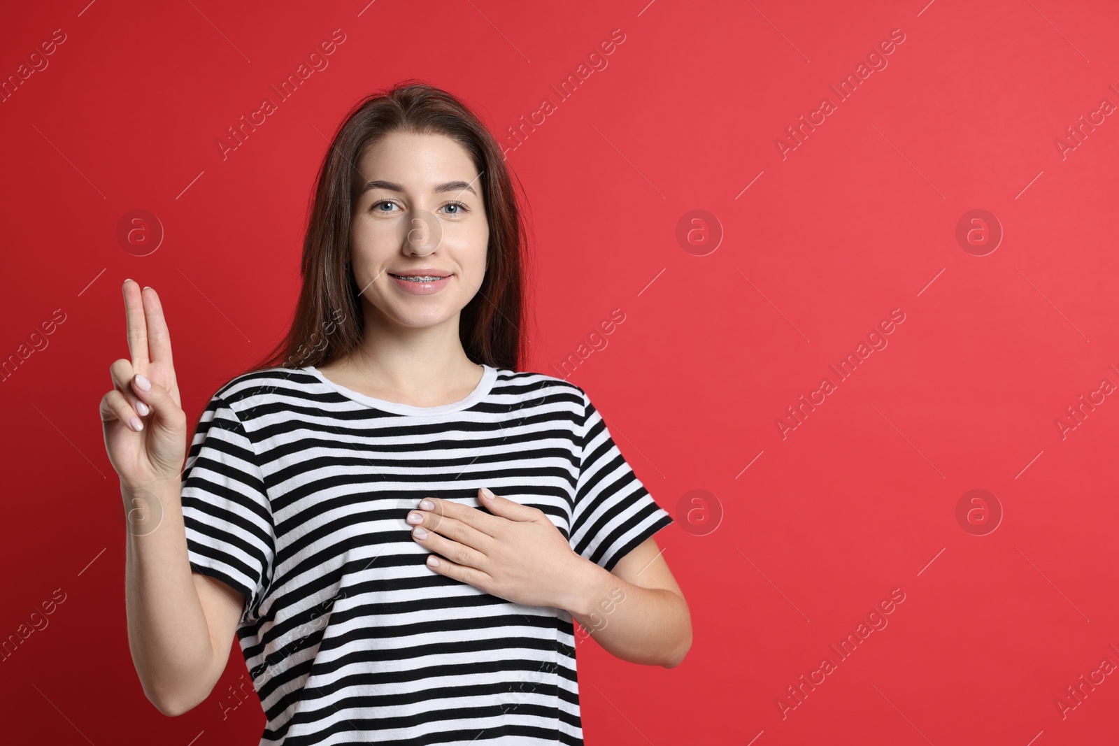 Photo of Woman showing oath gesture on red background, space for text. Making promise