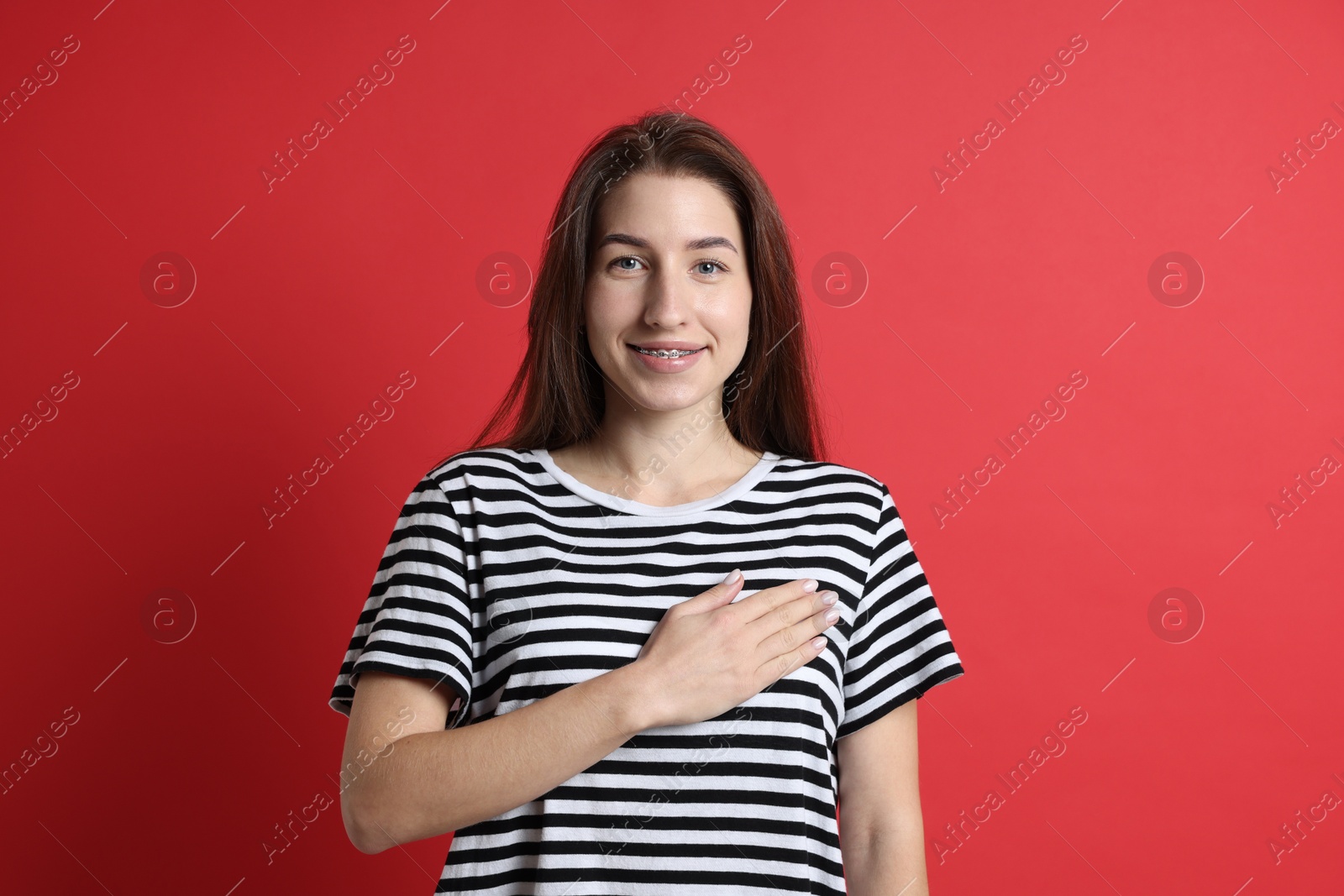 Photo of Woman making promise on red background. Oath gesture