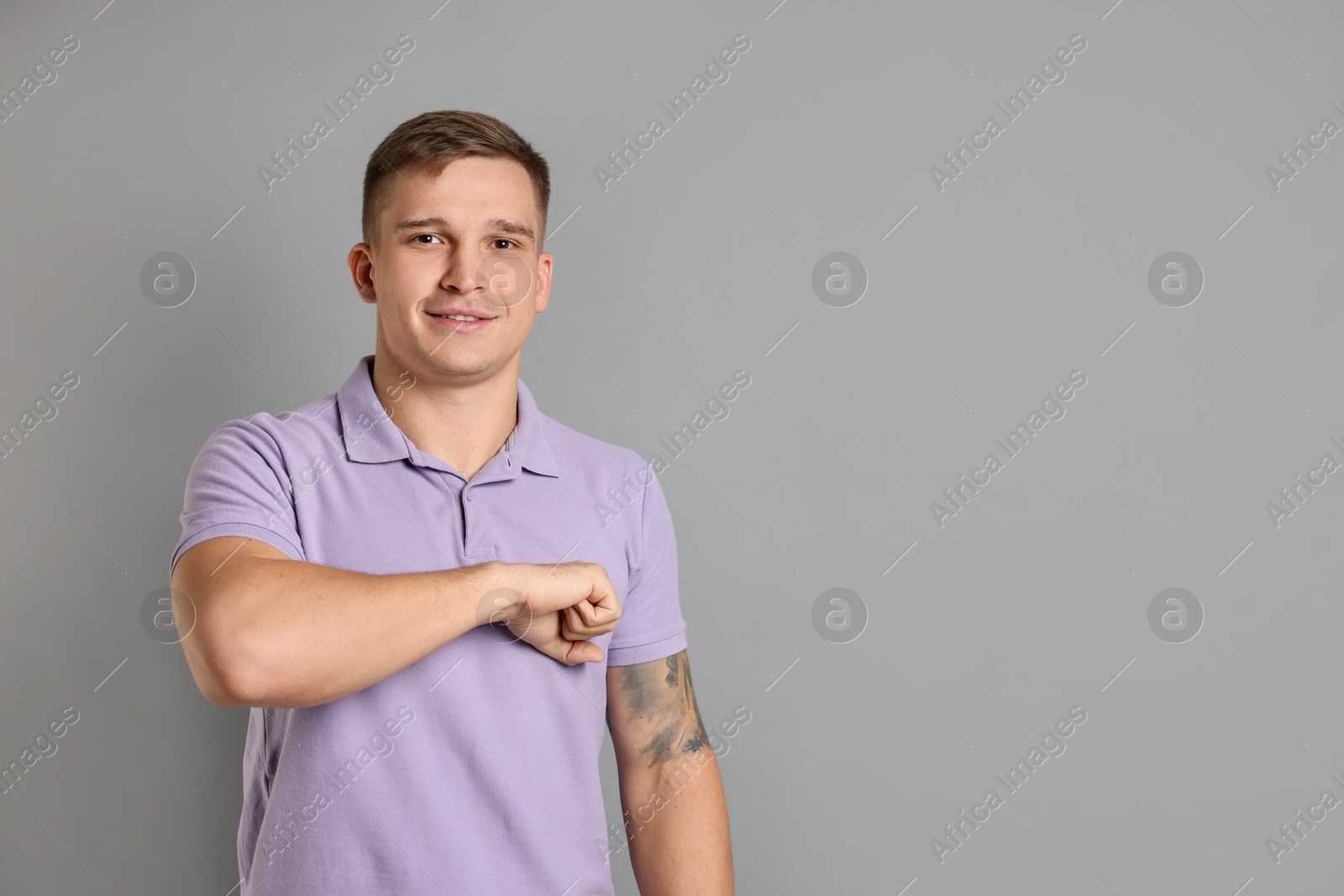 Photo of Man making promise on grey background, space for text. Oath gesture