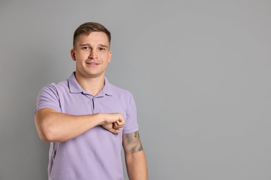 Photo of Man making promise on grey background, space for text. Oath gesture