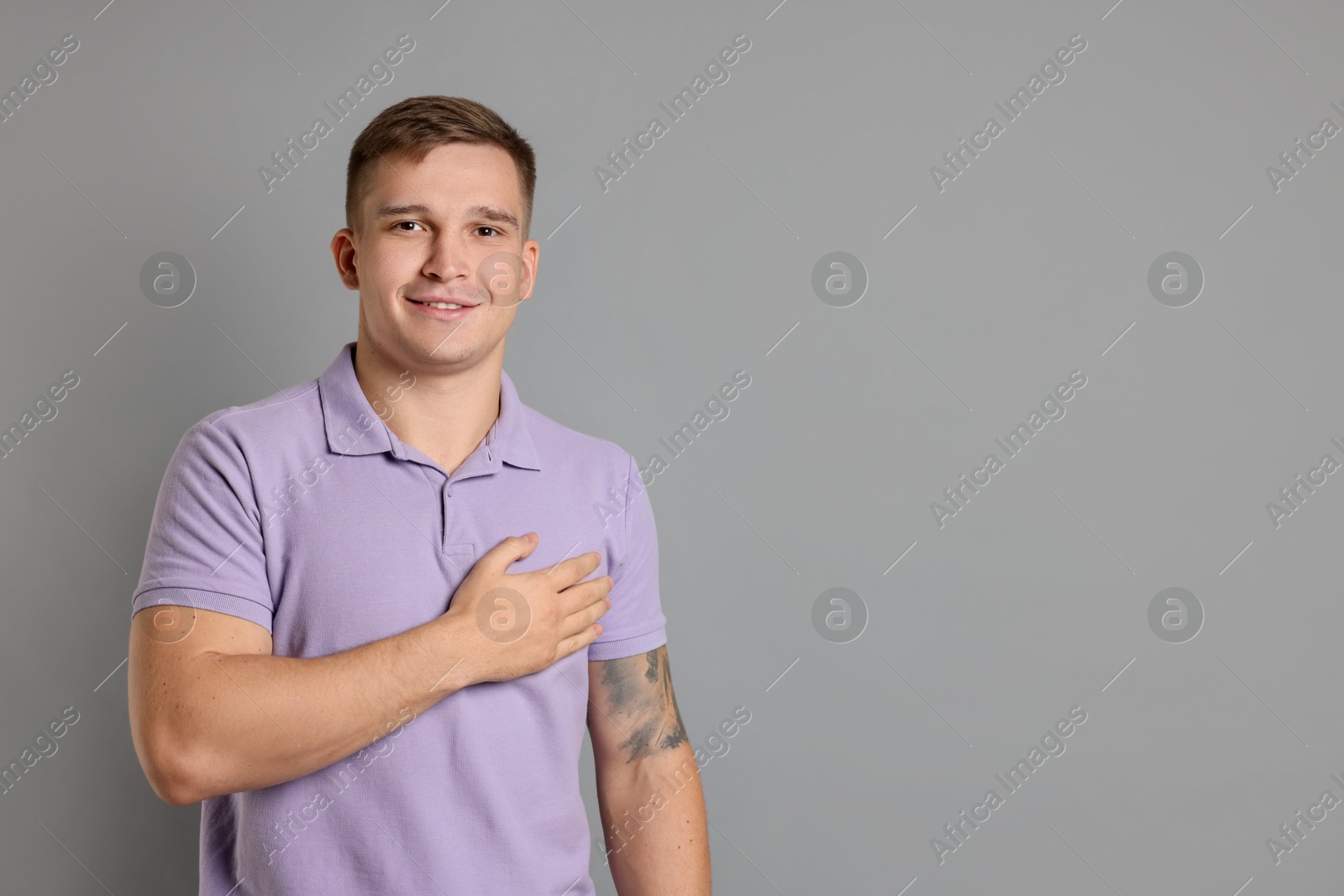 Photo of Man making promise on grey background, space for text. Oath gesture