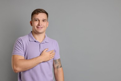 Photo of Man making promise on grey background, space for text. Oath gesture