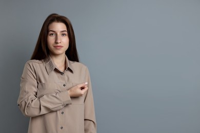 Woman making promise on grey background, space for text. Oath gesture