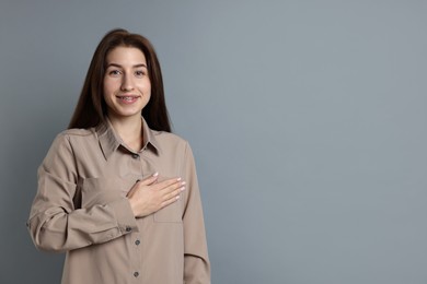 Photo of Woman making promise on grey background, space for text. Oath gesture