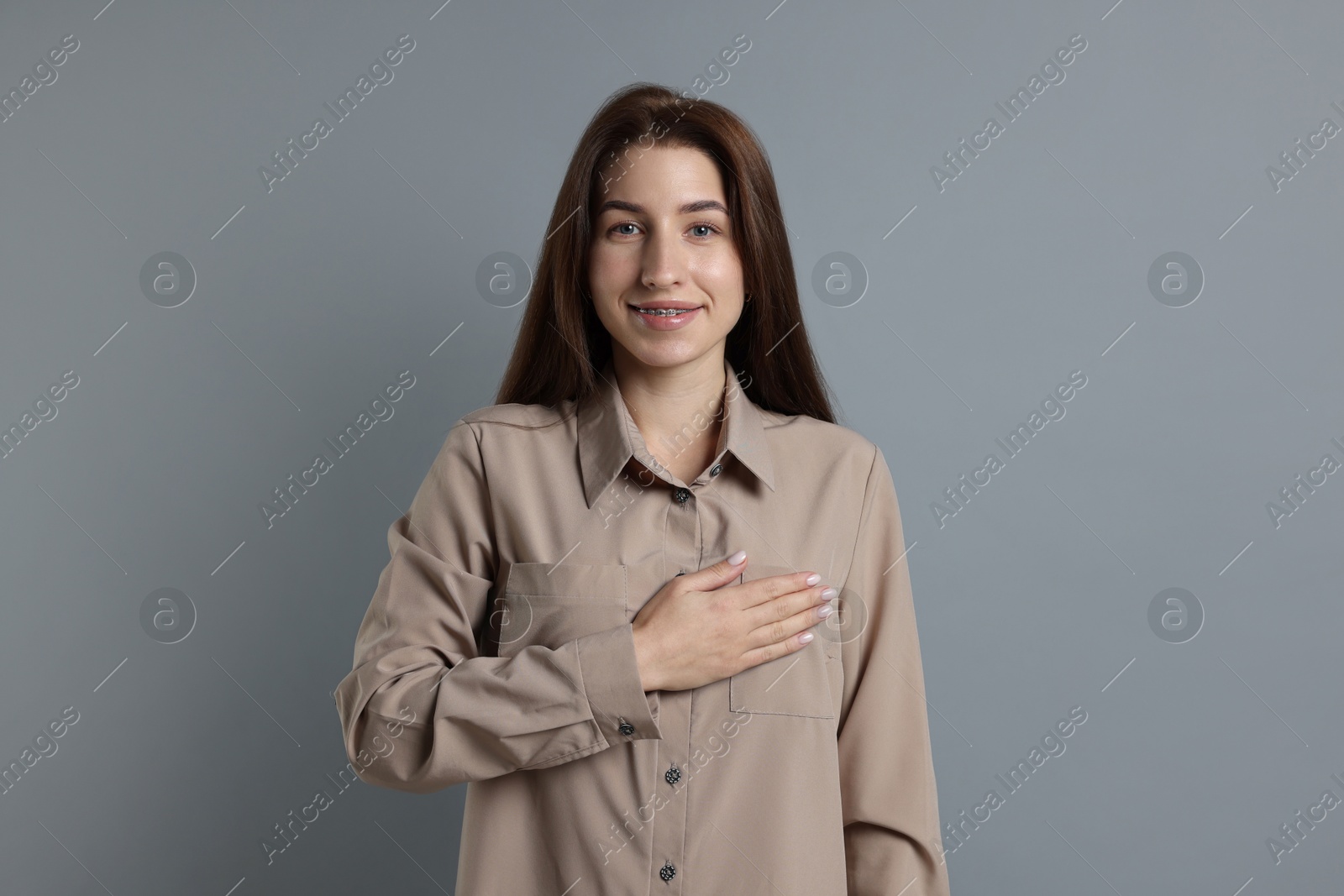 Photo of Woman making promise on grey background. Oath gesture