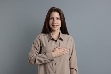 Photo of Woman making promise on grey background. Oath gesture