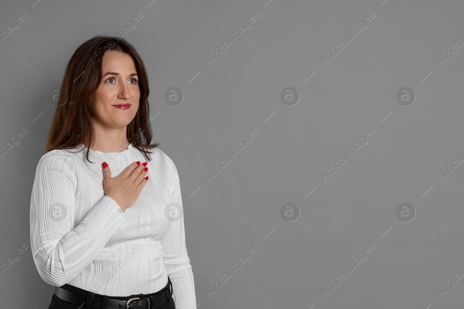 Photo of Woman making promise on grey background, space for text. Oath gesture