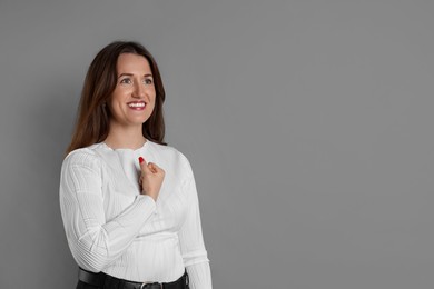 Photo of Woman making promise on grey background, space for text. Oath gesture