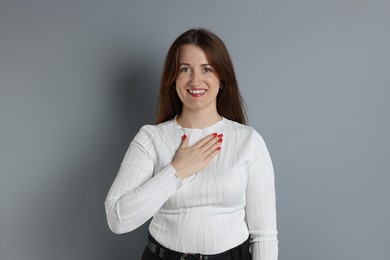 Woman making promise on grey background. Oath gesture