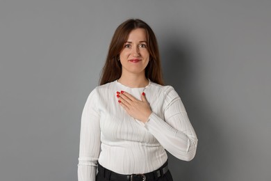 Photo of Woman making promise on grey background. Oath gesture