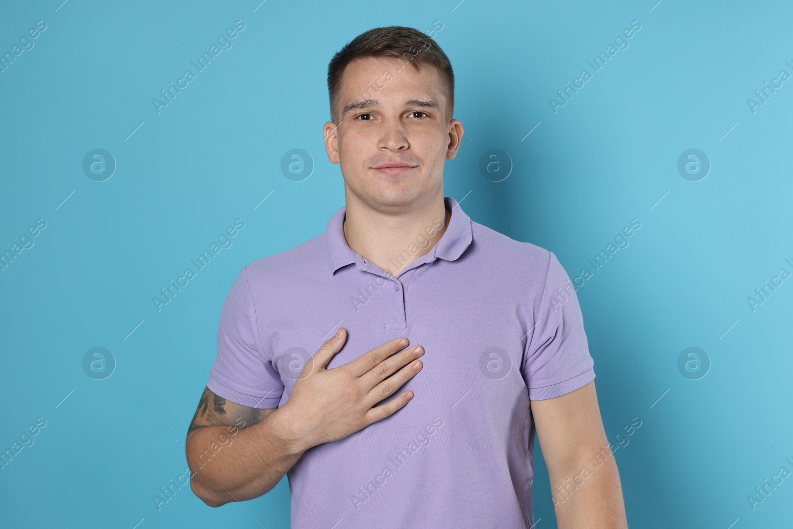 Photo of Man making promise on light blue background. Oath gesture