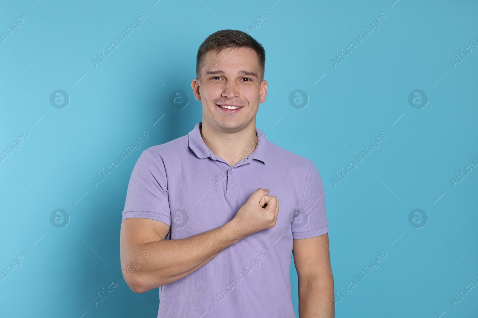 Photo of Man making promise on light blue background. Oath gesture