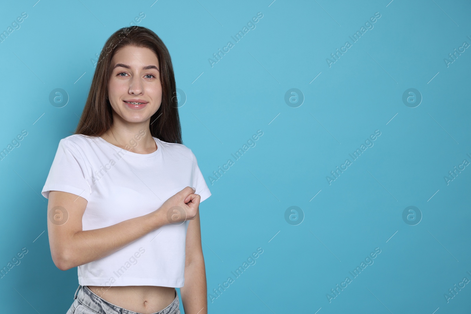 Photo of Woman making promise on light blue background, space for text. Oath gesture