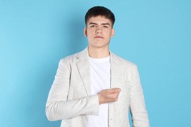 Photo of Man making promise on light blue background. Oath gesture