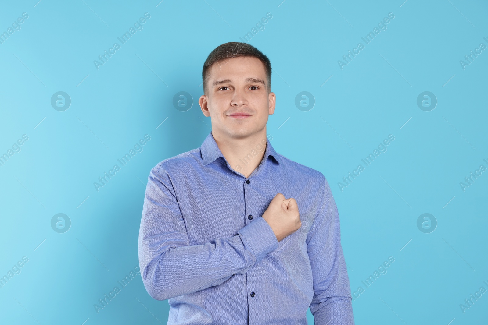 Photo of Man making promise on light blue background. Oath gesture