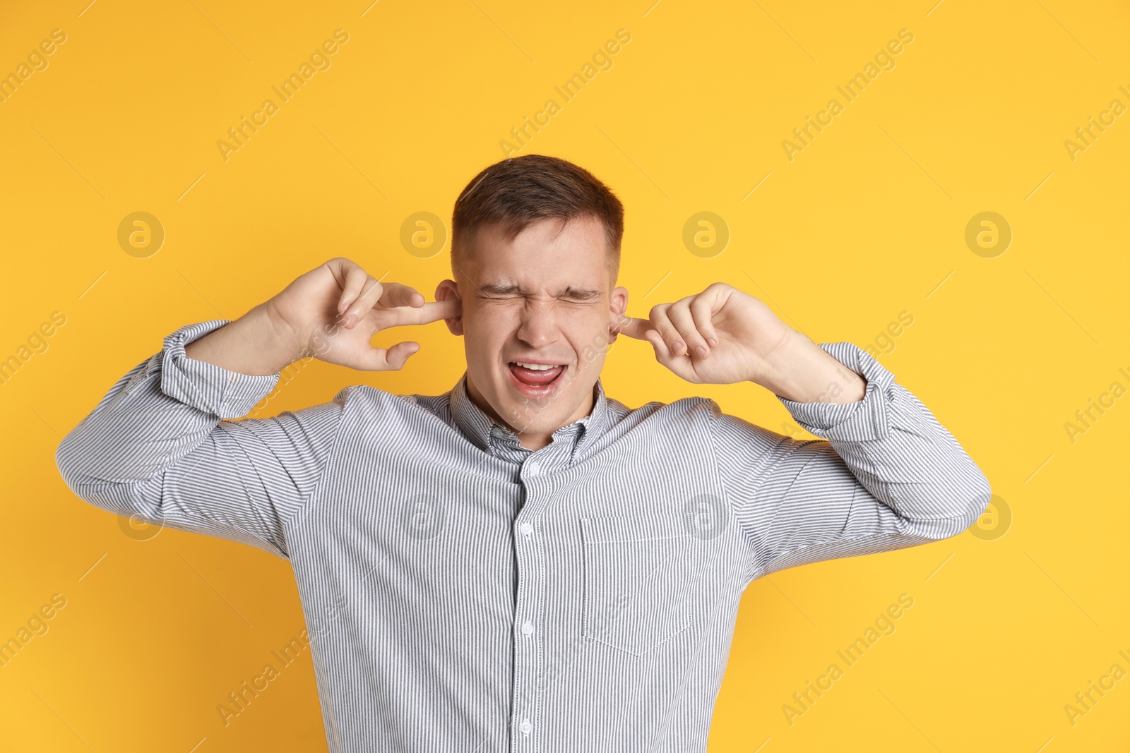 Photo of Man covering his ears with fingers on orange background