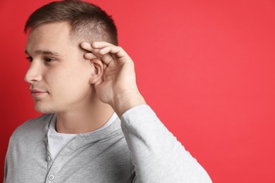 Photo of Man showing hand to ear gesture on red background, space for text