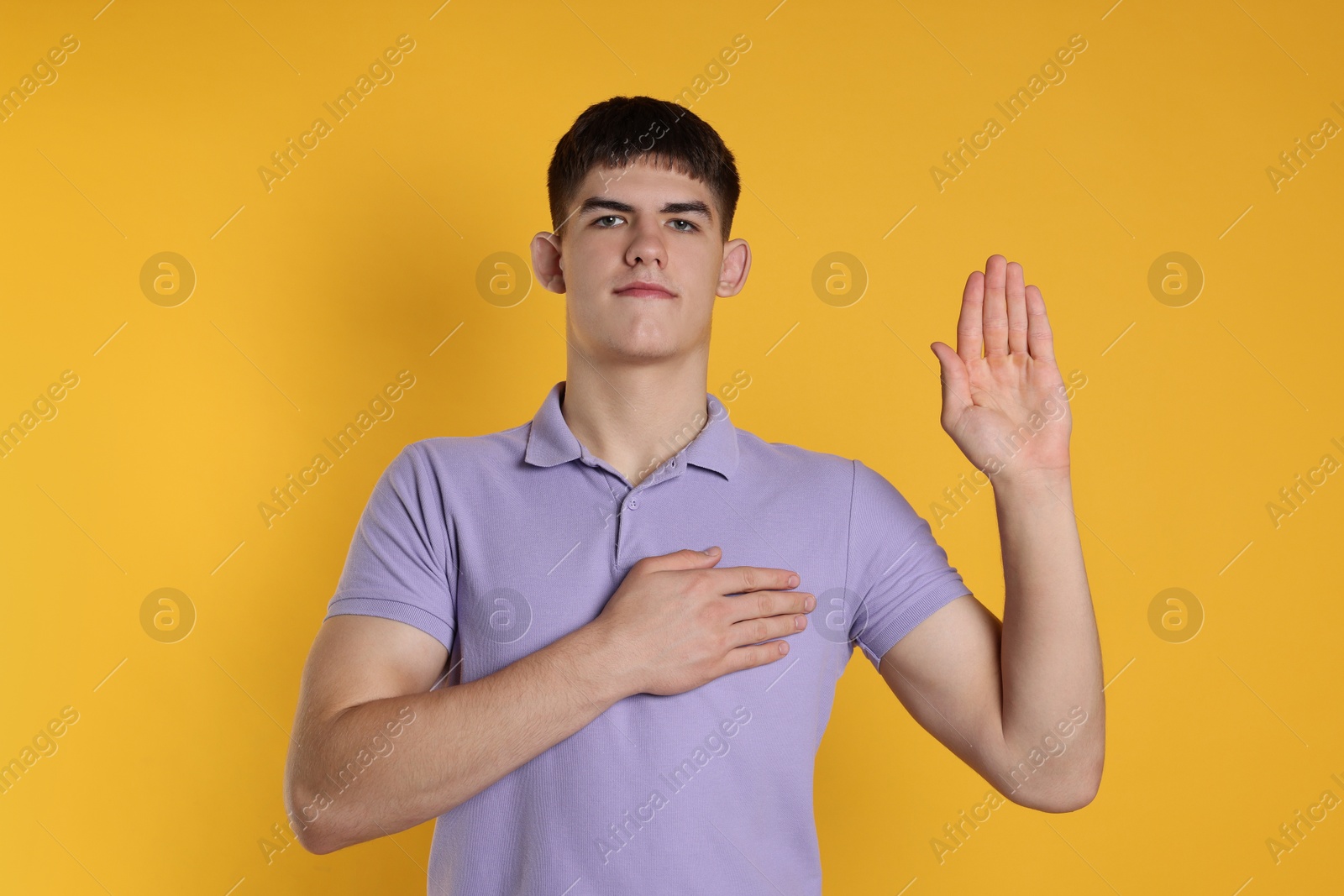 Photo of Man showing oath gesture on orange background