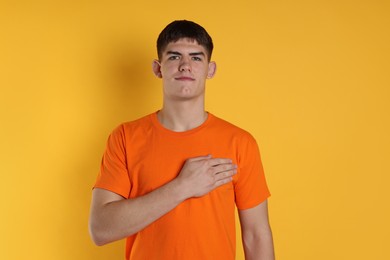 Photo of Man showing oath gesture on orange background