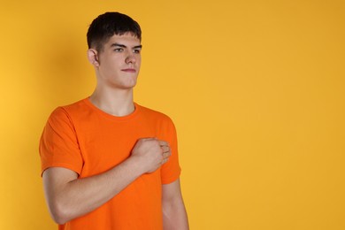 Photo of Man showing oath gesture on orange background. Space for text