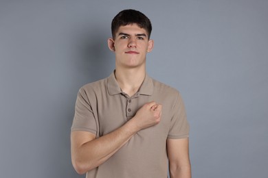 Man showing oath gesture on grey background