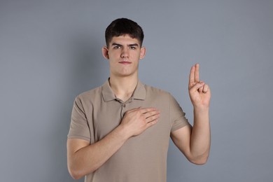 Photo of Man showing oath gesture on grey background