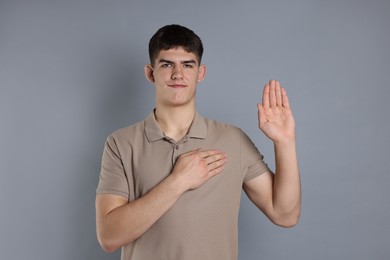 Man showing oath gesture on grey background