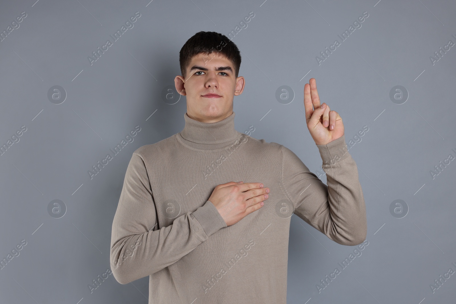 Photo of Man showing oath gesture on grey background