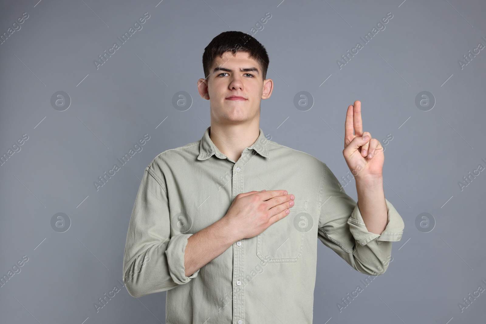 Photo of Man showing oath gesture on grey background