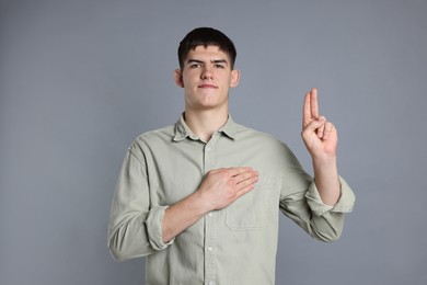 Man showing oath gesture on grey background