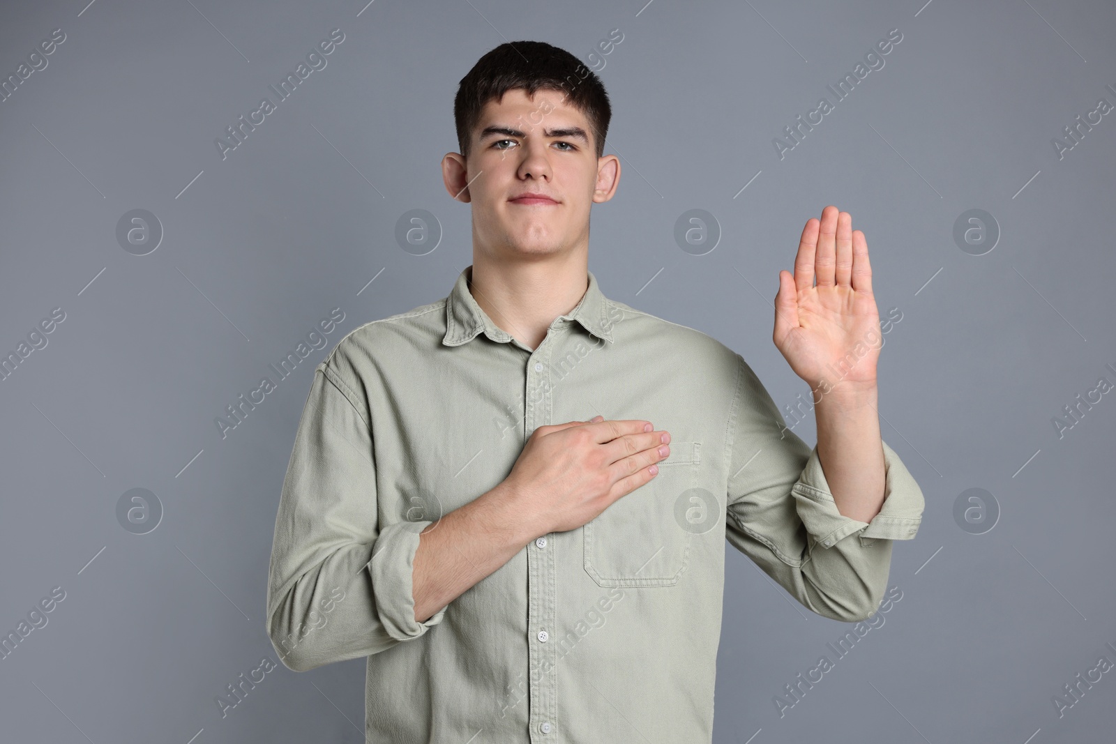 Photo of Man showing oath gesture on grey background