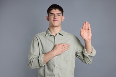 Photo of Man showing oath gesture on grey background