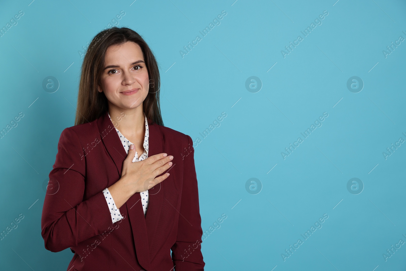 Photo of Woman making promise on light blue background, space for text. Oath gesture