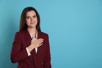 Photo of Woman making promise on light blue background, space for text. Oath gesture