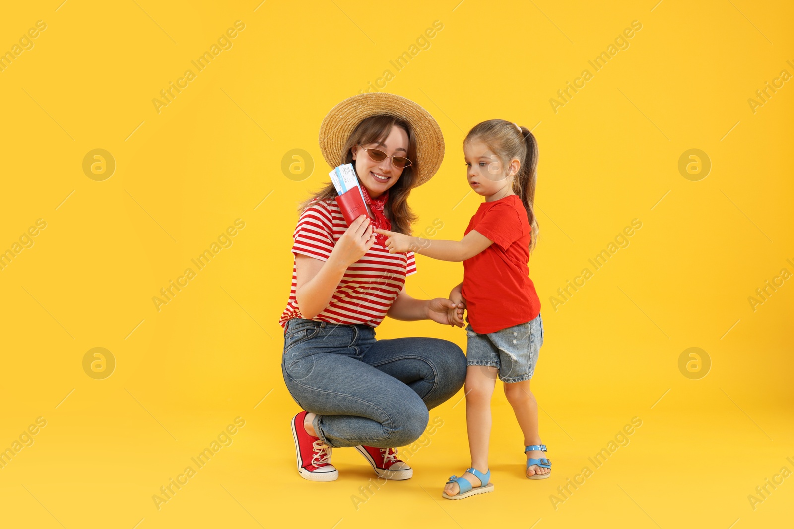 Photo of Traveller with passport and tickets. Young woman and cute little girl on yellow background