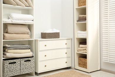 Photo of Home textile organization. Folded towels and blankets on shelving units indoors