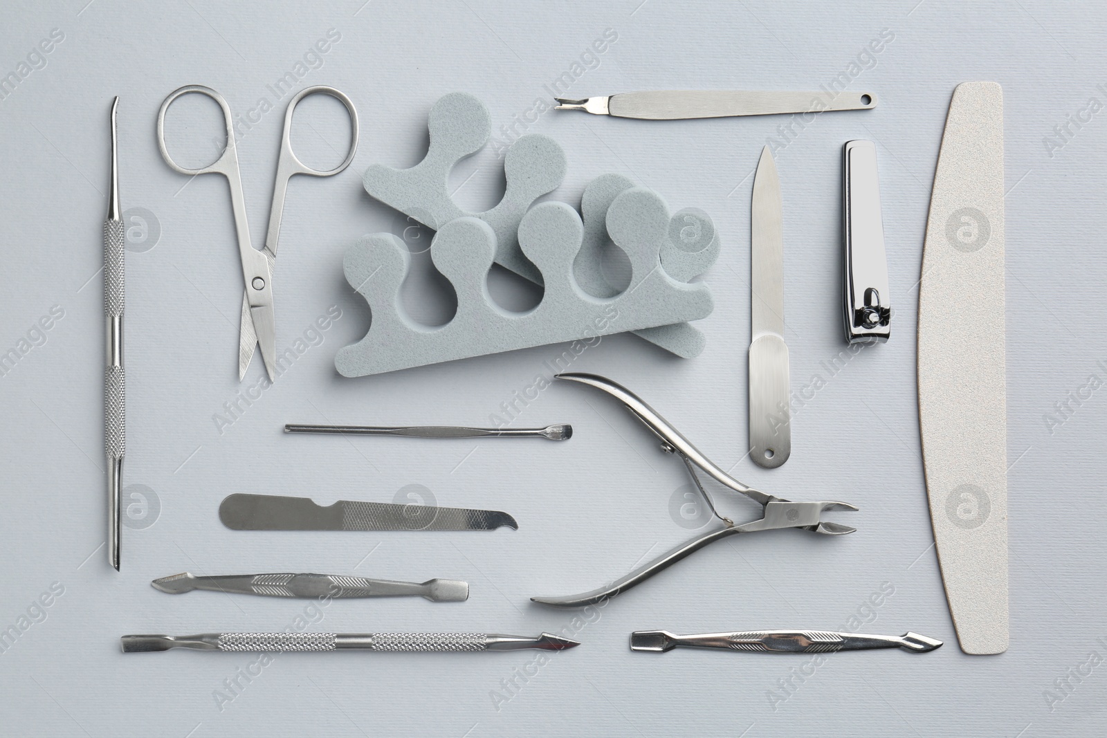 Photo of Set of pedicure tools on light grey background, flat lay