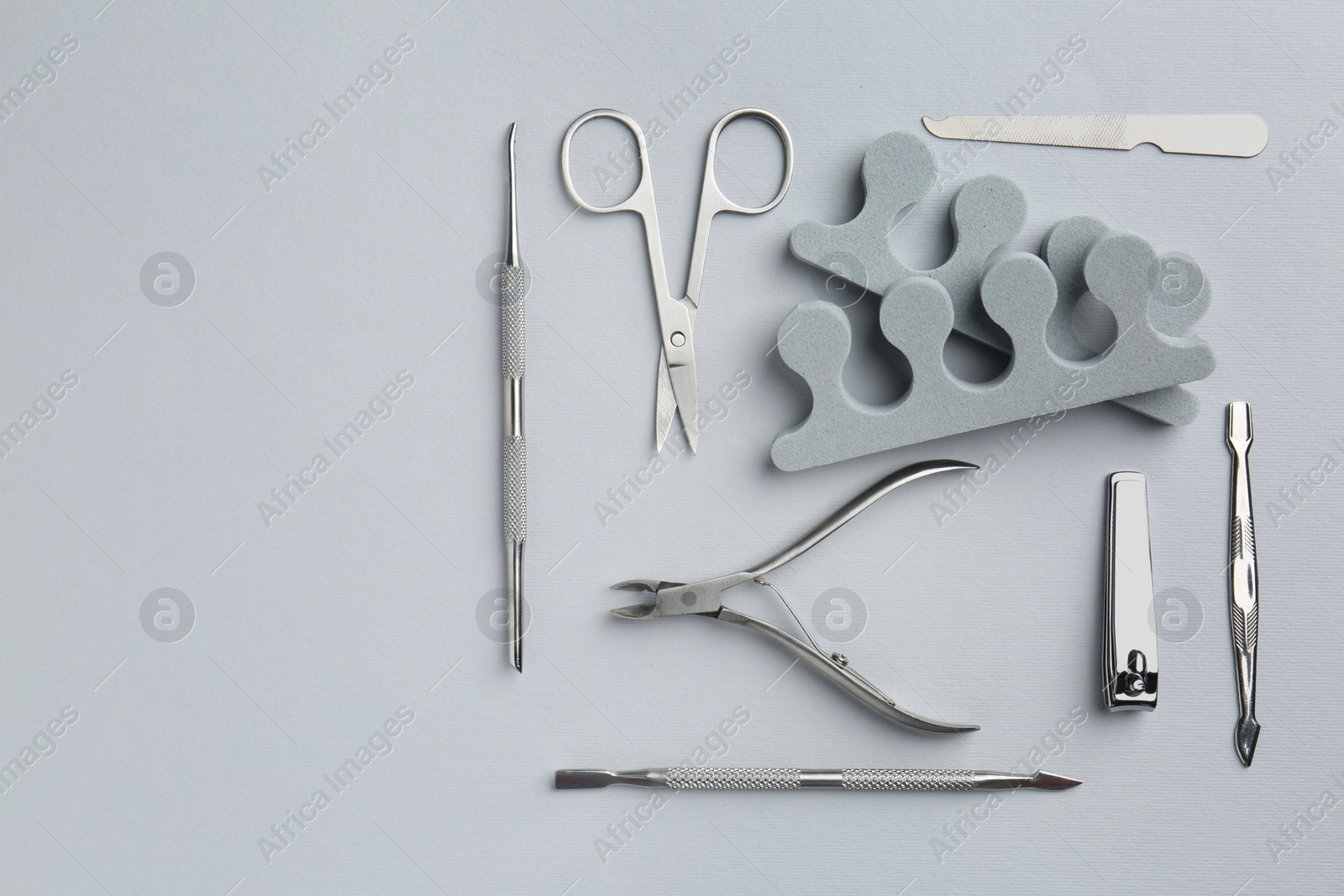 Photo of Set of pedicure tools on light grey background, flat lay. Space for text